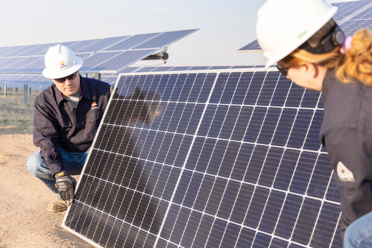 Dos operarios manejando un panel solar del proyecto de Repsol Jicarilla 2