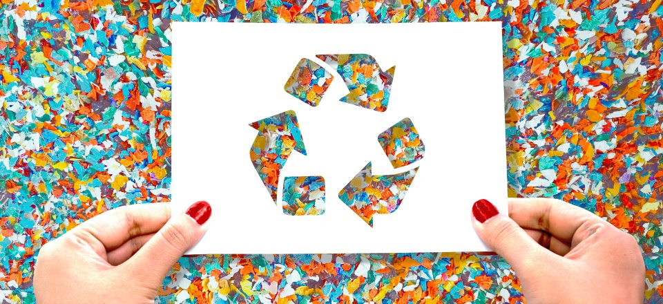 Recycled particles and hands holding paper with recycling symbol
